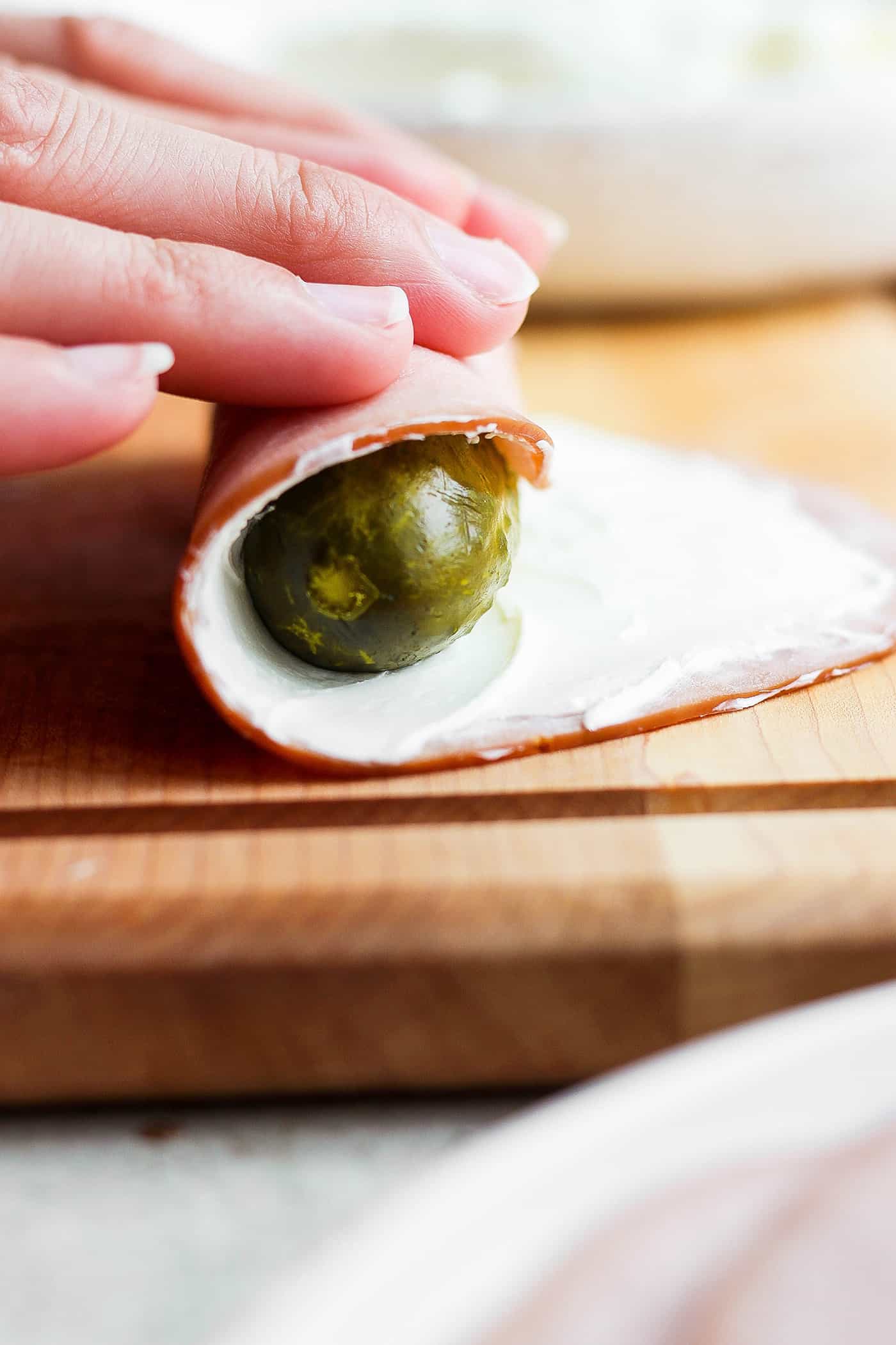 ickle Roll Ups are a 3-ingredient appetizer that's perfect for a party snack or anytime! Tangy pickles are filled with cream cheese and ham. Hands roll a pickle in a piece of ham spread with cream cheese.
