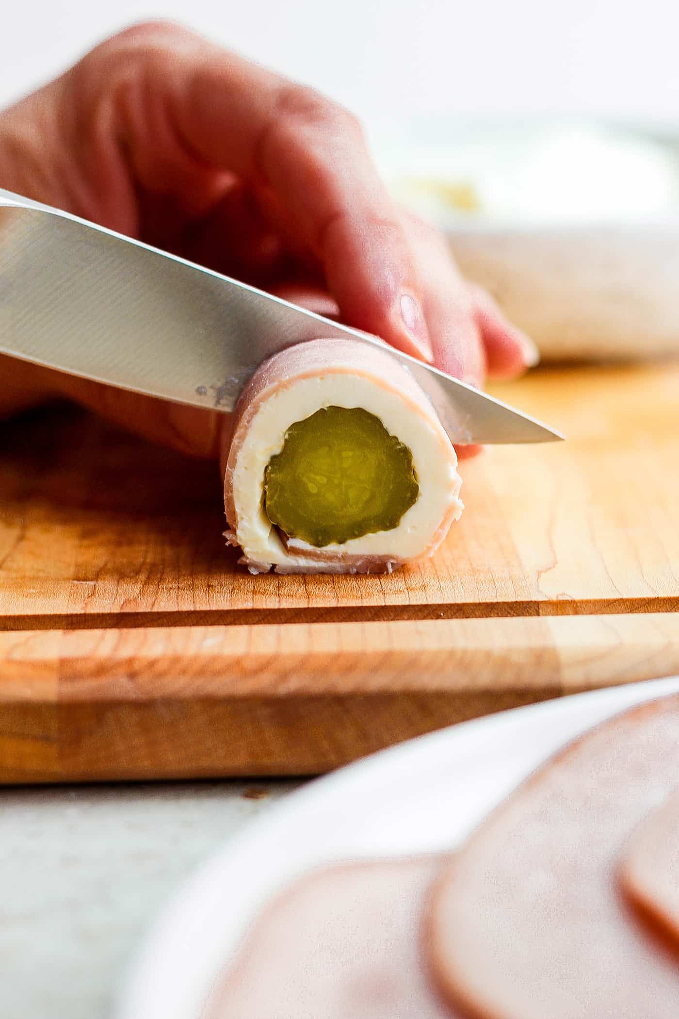 ickle Roll Ups are a 3-ingredient appetizer that's perfect for a party snack or anytime! Tangy pickles are filled with cream cheese and ham. A knife cuts a pickle roll up.