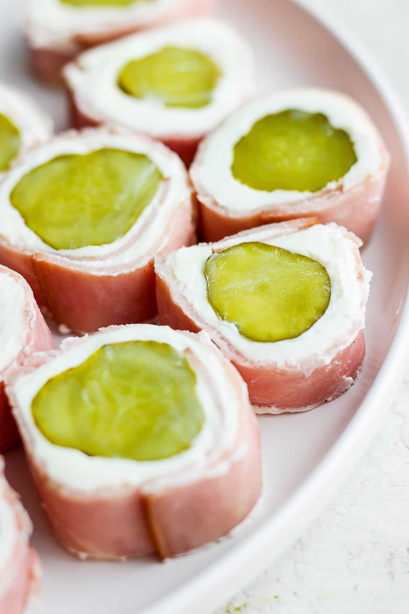 ickle Roll Ups are a 3-ingredient appetizer that's perfect for a party snack or anytime! Tangy pickles are filled with cream cheese and ham. Pickle roll up are shown on a plate.