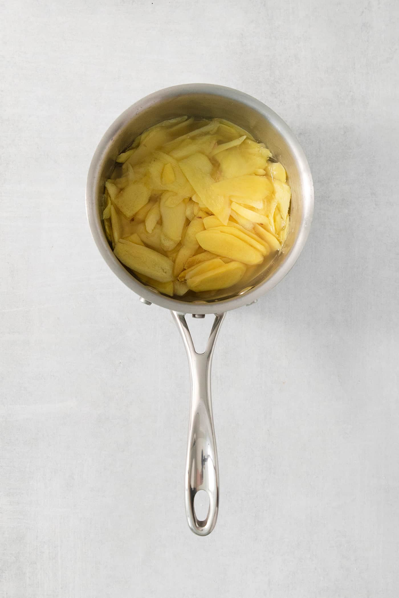 Peppery, pink Pickled Ginger is a wonderful companion to sushi and it's so easy to make at home! You need just 5 ingredients. Sliced ginger in a pot.