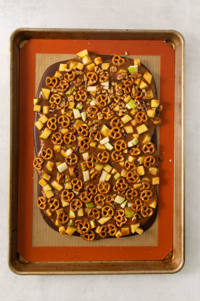 This Caramel Apple Bark is a fun treat to make when you want the flavor of a fresh caramel apple without the hassle. Pretzels on top of caramel and apples on a baking sheet to make bark.