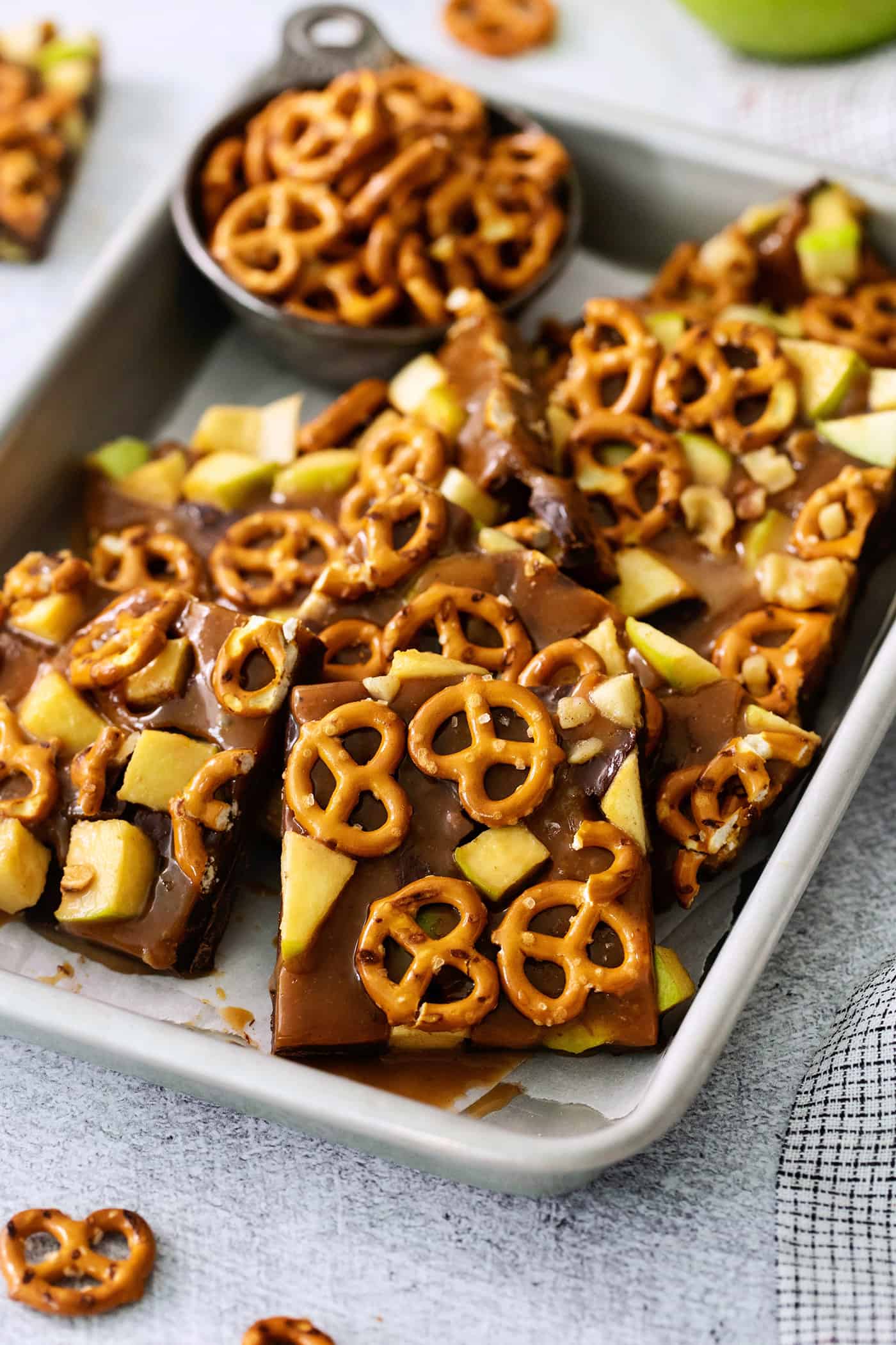 This Caramel Apple Bark is a fun treat to make when you want the flavor of a fresh caramel apple without the hassle. Cut up pieces of caramel apple bark are seen on a baking tray.