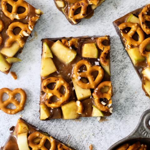 An overhead shot of pieces of caramel apple bark with pretzels on a white background.