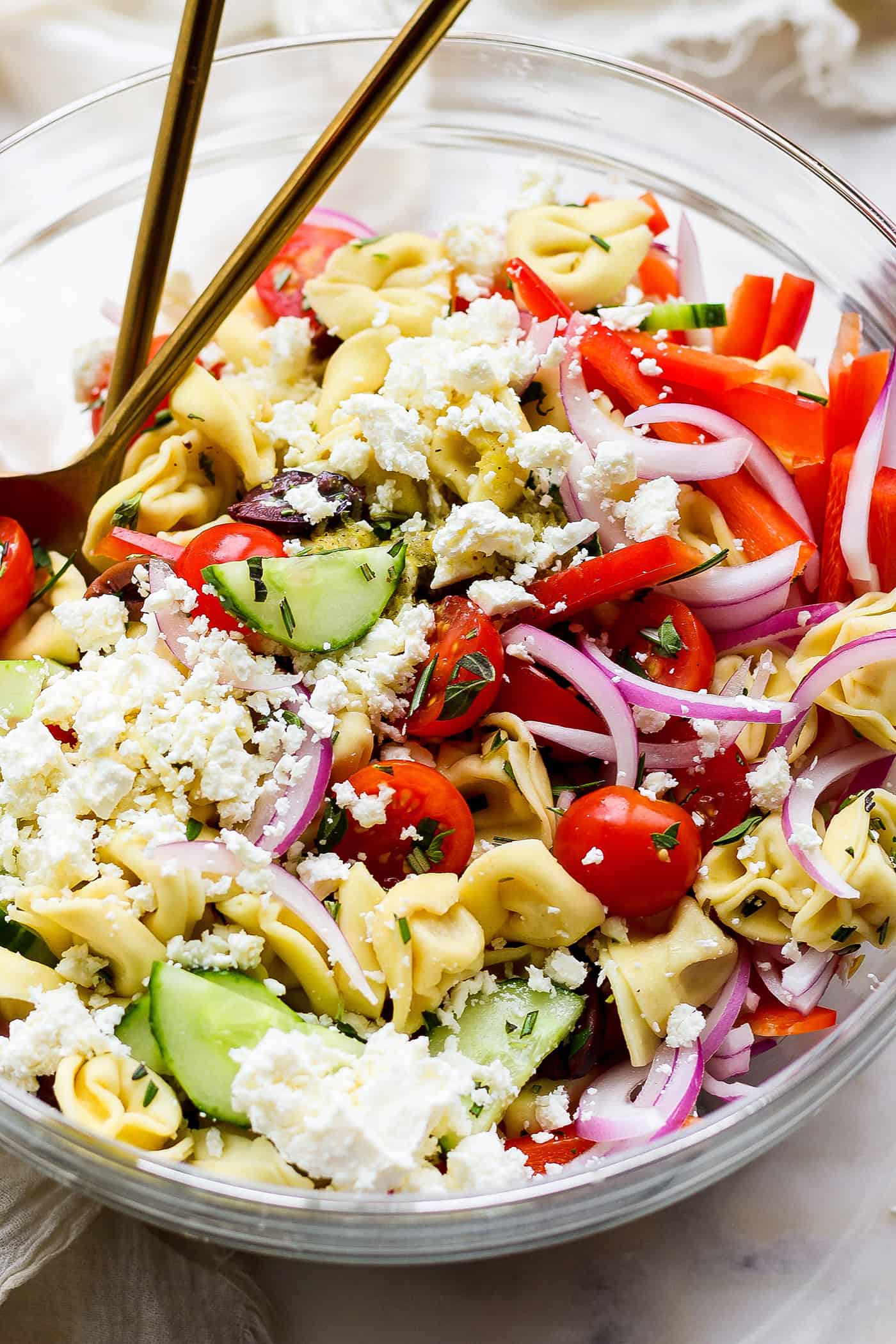 reek Tortellini Salad is full of fresh Greek flavors like lemon, olive oil, herbs, and feta cheese! This cold salad is great at picnics. A close up of Greek tortellini salad.