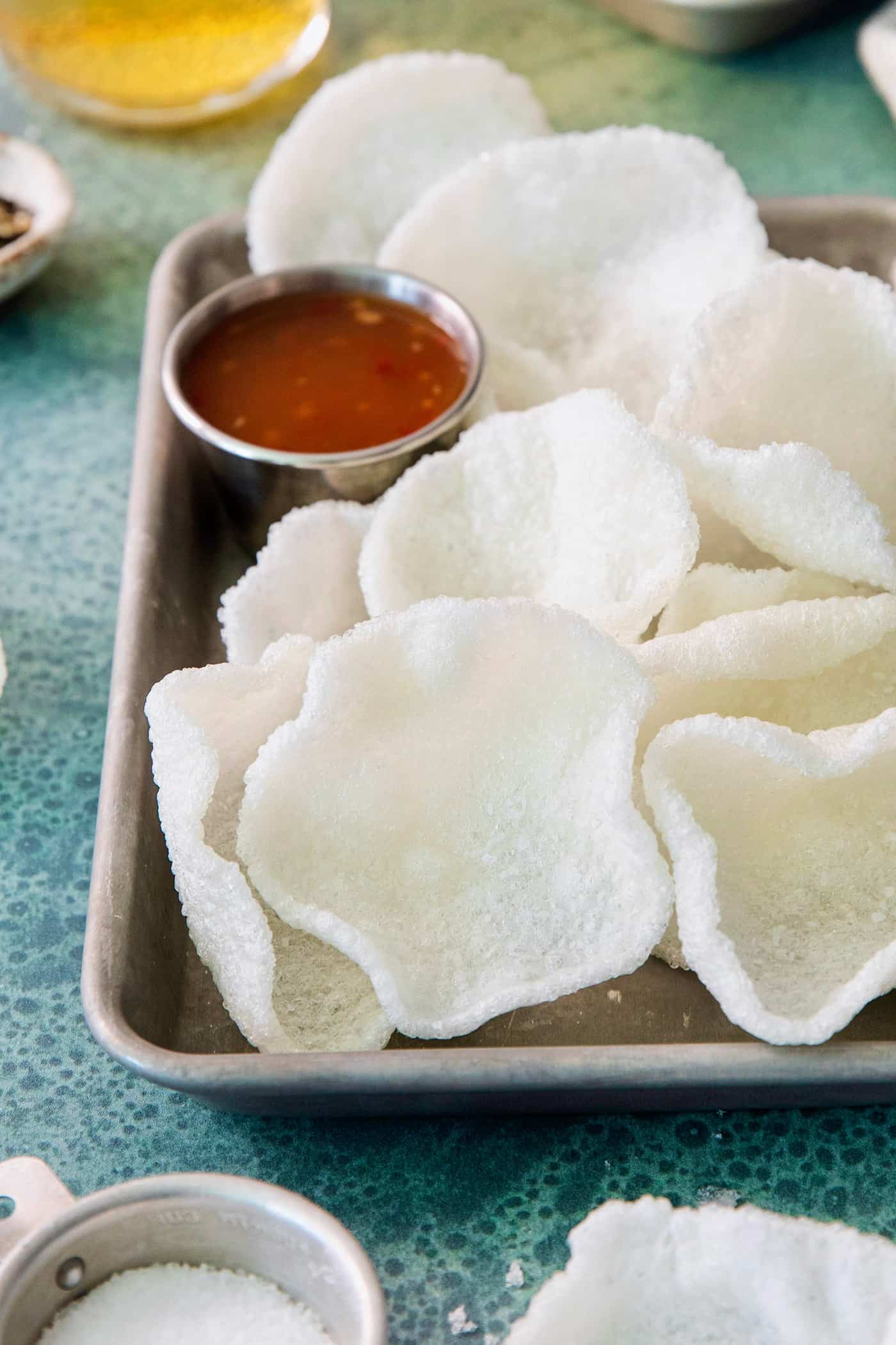 Shrimp Chips are a quick snack that will satisfy your craving for something with a salty crunch and a light umami flavor. A tray of shrimp chips with a dish of chili sauce.