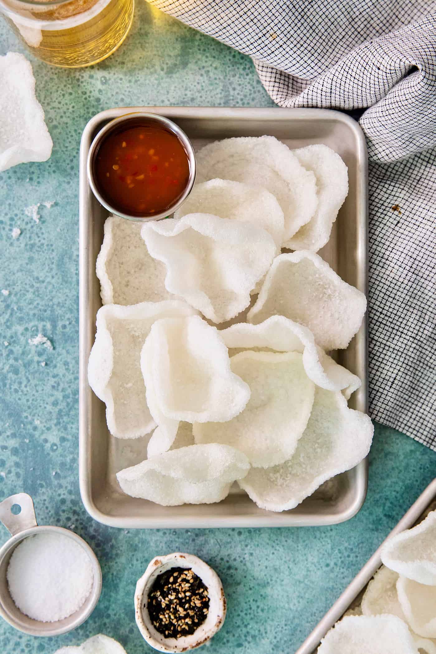 Shrimp Chips are a quick snack that will satisfy your craving for something with a salty crunch and a light umami flavor. A tray of shrimp chips with a dish of chili sauce.