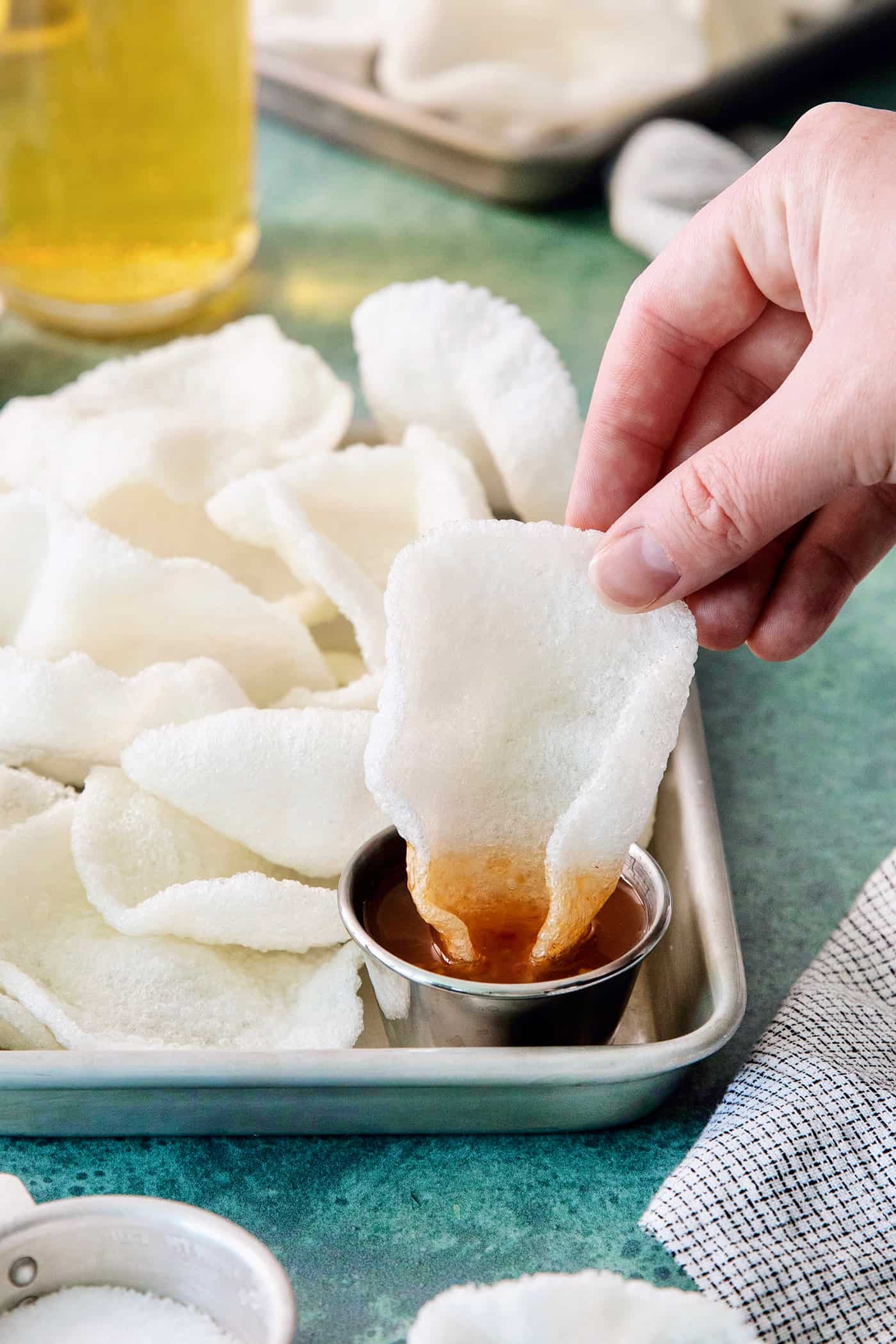 Shrimp Chips are a quick snack that will satisfy your craving for something with a salty crunch and a light umami flavor. A hand dips a shrimp dip into sauce.