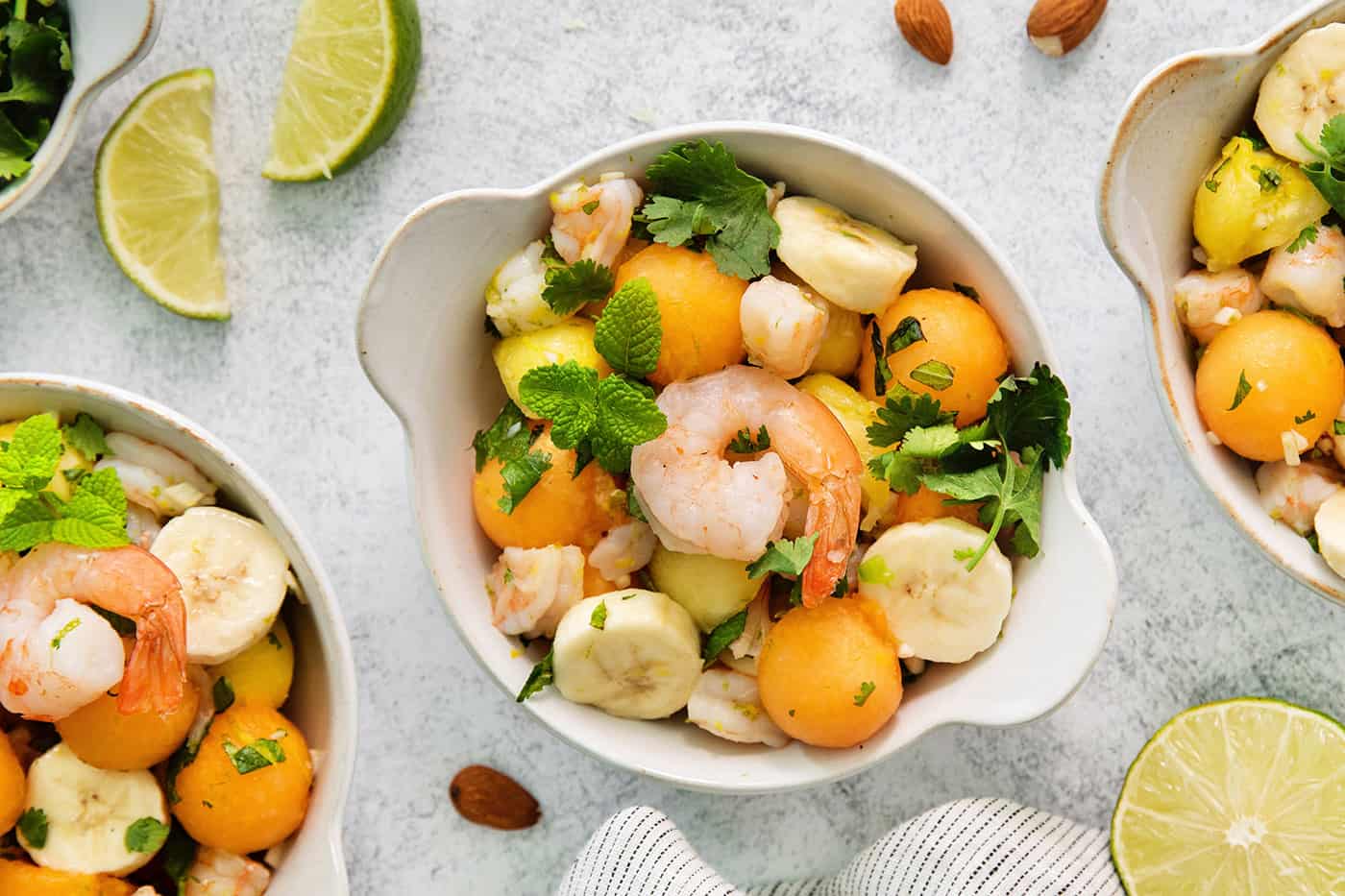 This Tropical Shrimp Salad has fresh, bright color and flavor. It's a unique, refreshing appetizer or salad recipe that's great for entertaining! An overhead shot of bowls of tropical shrimp salad on a white background.
