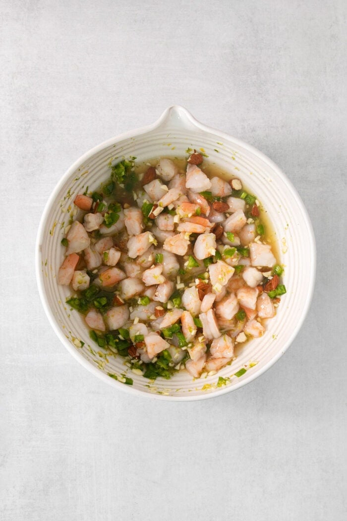 This Tropical Shrimp Salad has fresh, bright color and flavor. It's a unique, refreshing appetizer or salad recipe, great for entertaining! Shrimp is added to dressing in a white bowl to make tropical shrimp salad.