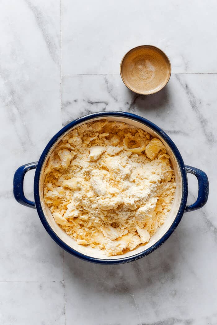 Comforting Beef Pot Pie is packed with tender beef and vegetables tucked into a stout-based gravy with flaky pie crust balanced on top. Butter is crumbled into flour for pie dough.