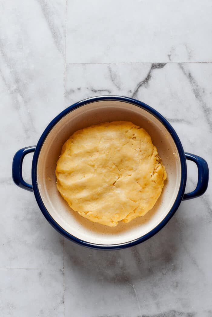 Comforting Beef Pot Pie is packed with tender beef and vegetables tucked into a stout-based gravy with flaky pie crust balanced on top. A ball of pie dough is seen in a pot.