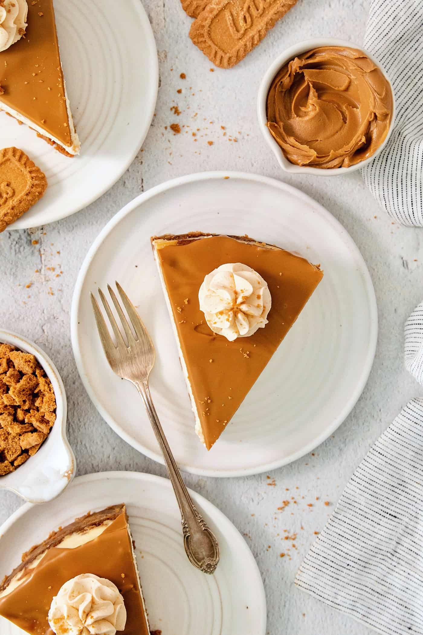 This Biscoff Cheesecake balances a rich cream cheese layer swirled with Biscoff cookie butter on a buttery cookie crust. Slices of biscoff cheesecake are shown on white plates.
