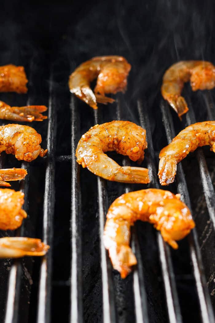 Juicy, flavorful Grilled Shrimp is ready in just minutes! Tender shrimp is bathed in an easy, sweet-smoky marinade and served with lemon. Shrimp is shown cooking on the grill.