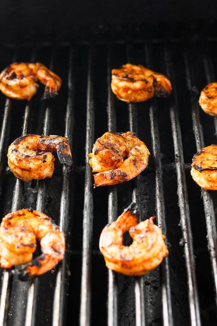 Juicy, flavorful Grilled Shrimp is ready in just minutes! Tender shrimp is bathed in an easy, sweet-smoky marinade and served with lemon. Shrimp is shown cooking on the grill.