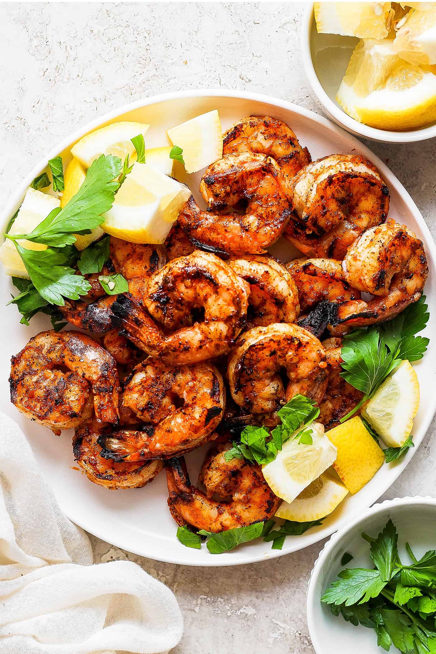 Juicy, flavorful Grilled Shrimp is ready in just minutes! Tender shrimp is bathed in an easy, sweet-smoky marinade and served with lemon. A platter of grilled shrimp surrounded by lemon wedges.