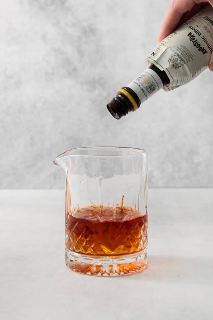 This classic Old Fashioned is a go-to before-dinner cocktail! It’s simple and easy, made with just three ingredients: whiskey, simple syrup, and bitters. Bitters are poured into a cocktail glass.