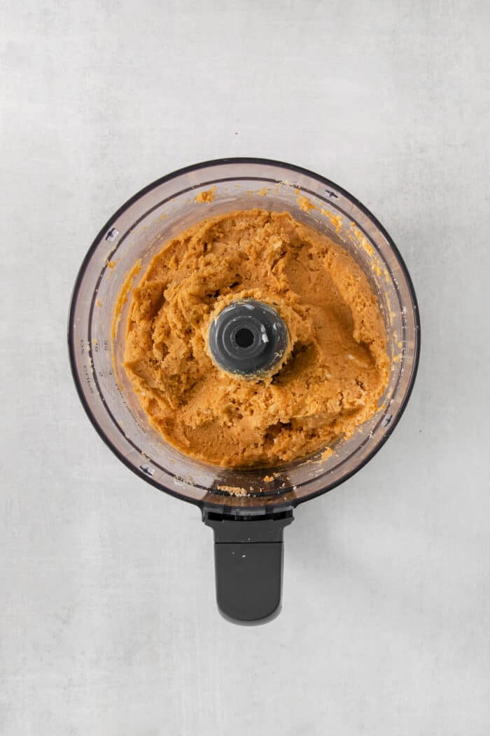 These Pumpkin Pie Truffles are the perfect fall treat! The truffle filling is made with crisp cookies, cream cheese, pumpkin puree, and spice. A food processor full of pumpkin pie truffle mix.