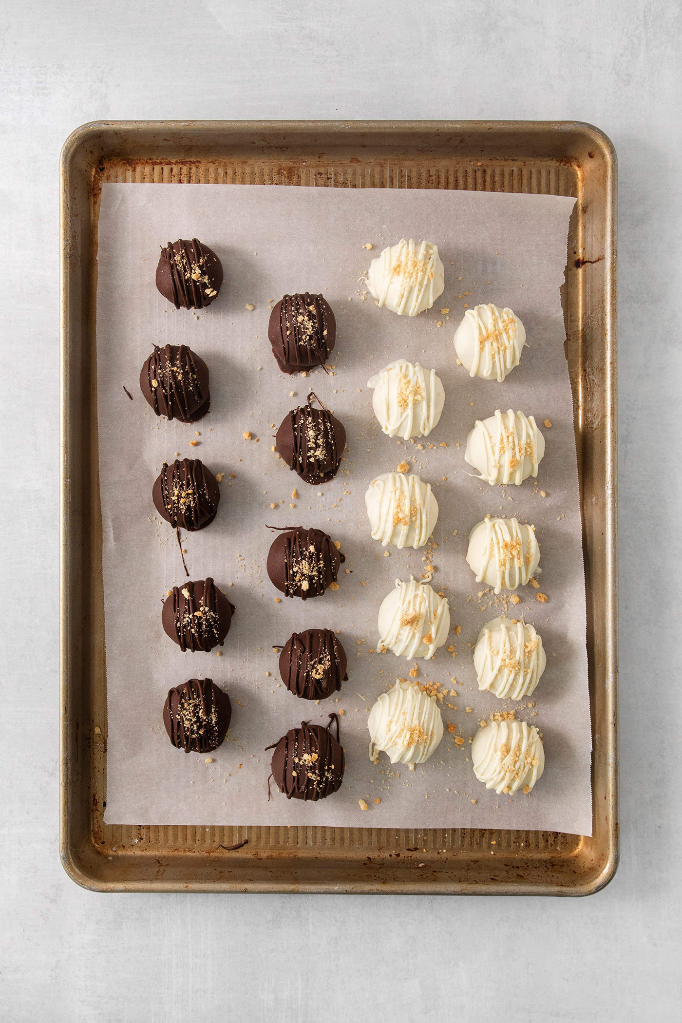 These Pumpkin Pie Truffles are the perfect fall treat! The truffle filling is made with crisp cookies, cream cheese, pumpkin puree, and spice. A baking tray holds pumpkin pie truffles, some covered with white chocolate and some covered with dark chocolate.