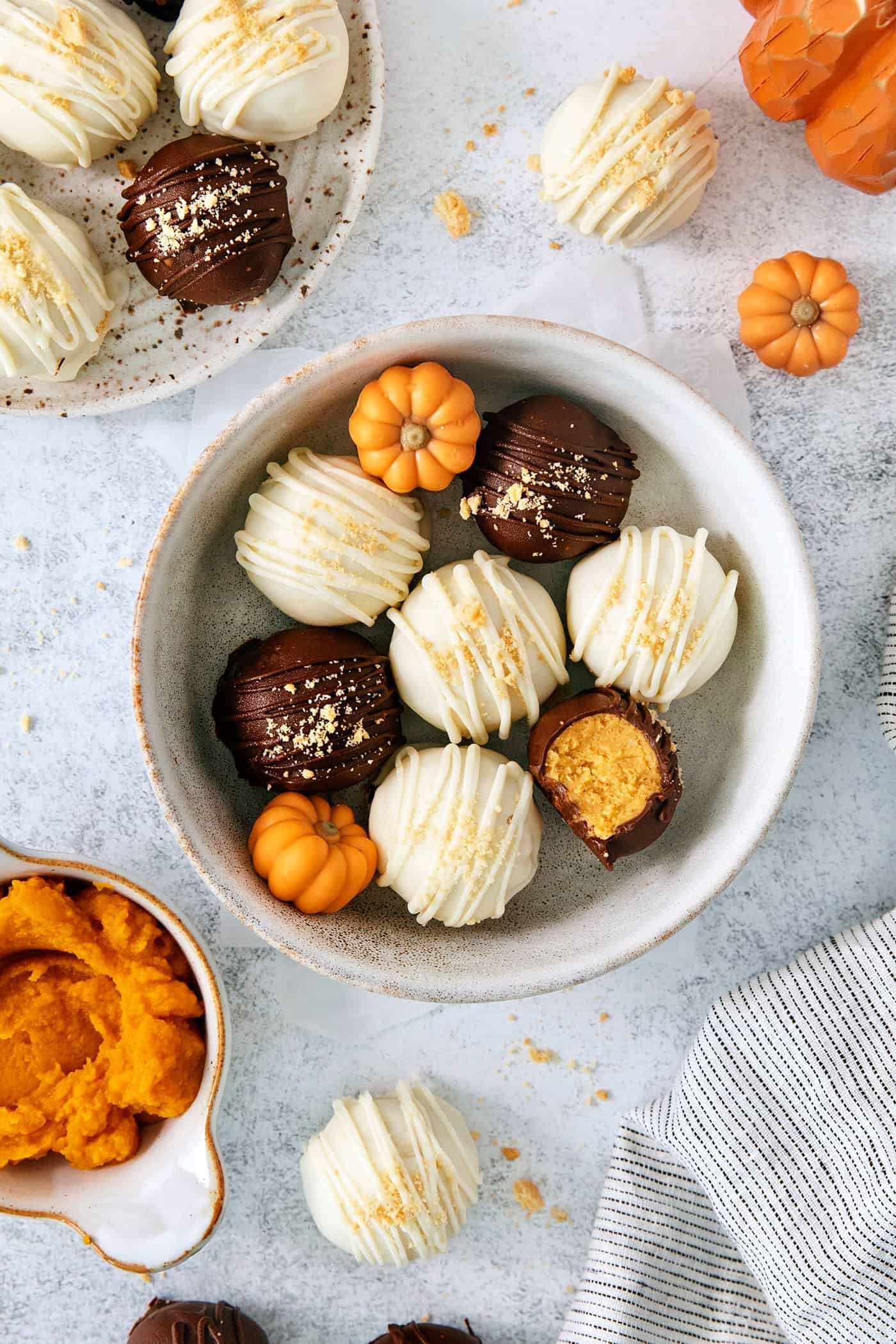 These Pumpkin Pie Truffles are the perfect fall treat! The truffle filling is made with crisp cookies, cream cheese, pumpkin puree, and spice. A top down shot of a white bowl of pumpkin pie truffles.