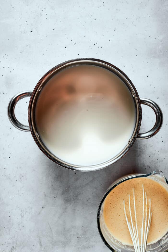 Napoleon Cake takes flaky homemade pastry and layers it with a sumptuous egg custard to make a creamy and cool dessert! A top down view of a pot of milk.