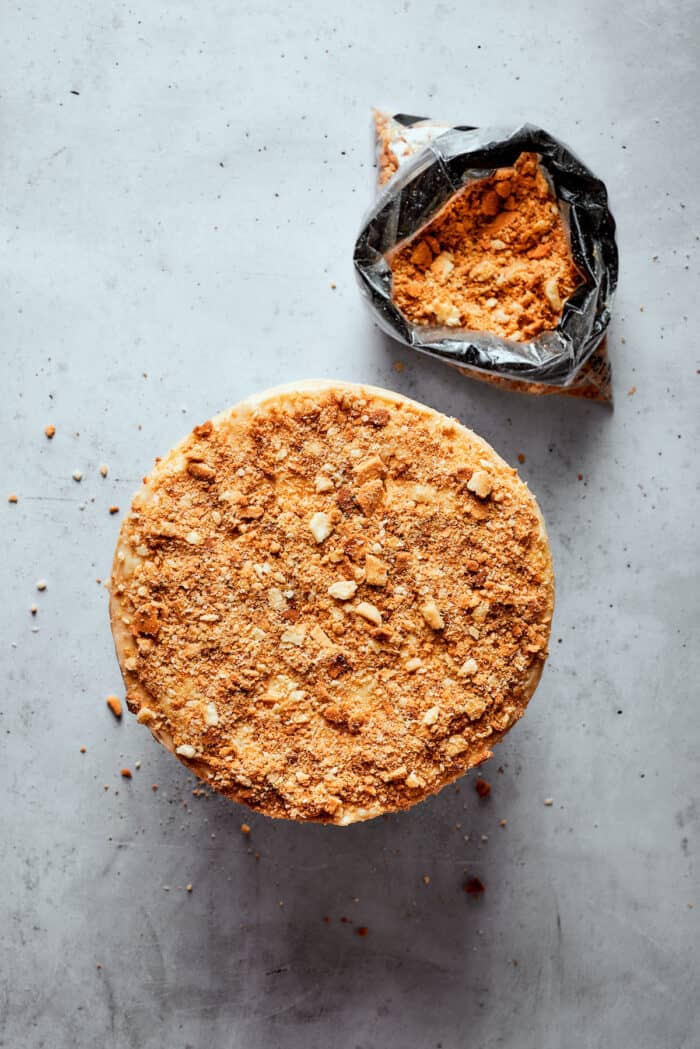 Napoleon Cake takes flaky homemade pastry and layers it with a sumptuous egg custard to make a creamy and cool dessert! A top down view of a Napoleon cake with a bowl of crushed pastry crumbs next to it.