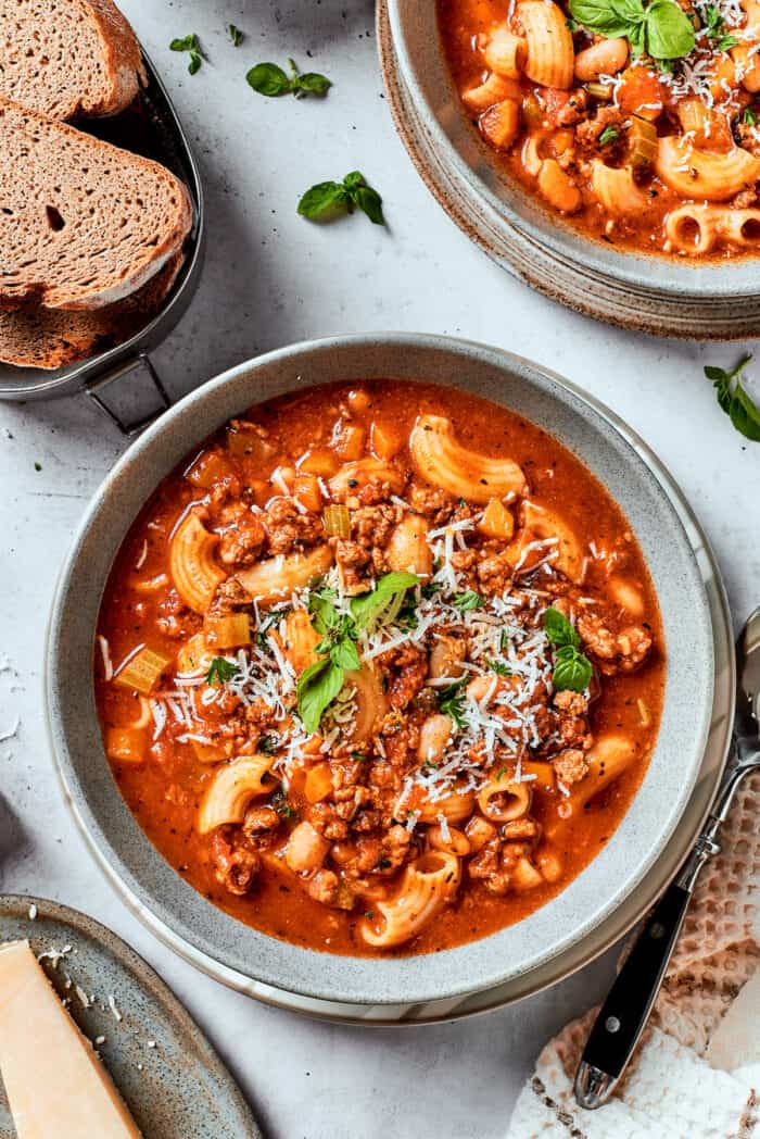 Easy, Italian-inspired Pasta Fazool is a wonderful soup that pairs creamy white beans with ground meat and pasta in a tomato-based broth. A top down shot of bowls of pasta fazool on a table.