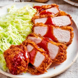 sauce drizzled over sliced pork katsu on a plate