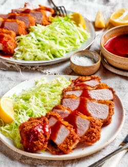 2 plates with sliced pork katsu and cabbage