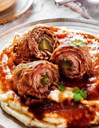 mashed potatoes, gravy, and pieces of rouladen sliced open to reveal the rolled-up interiors