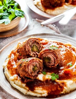 mashed potatoes, gravy, and pieces of rouladen sliced open to reveal the rolled-up interiors
