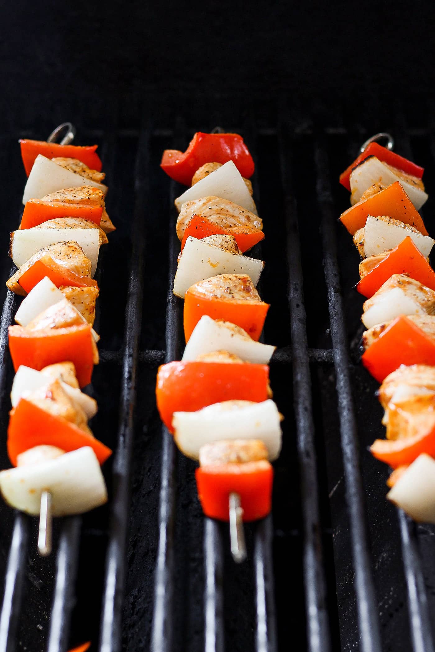 Sweet-spicy Chipotle Honey Chicken Kabobs bathe tender chicken in a honey-infused vinaigrette with a kick of spice. Chipotle honey chicken skewers are shown cooking on the grill.