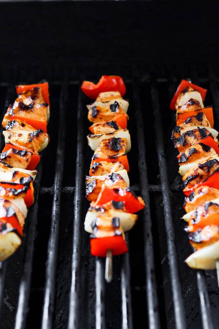 Sweet-spicy Chipotle Honey Chicken Kabobs bathe tender chicken in a honey-infused vinaigrette with a kick of spice. Chipotle honey chicken skewers are shown cooking on the grill.