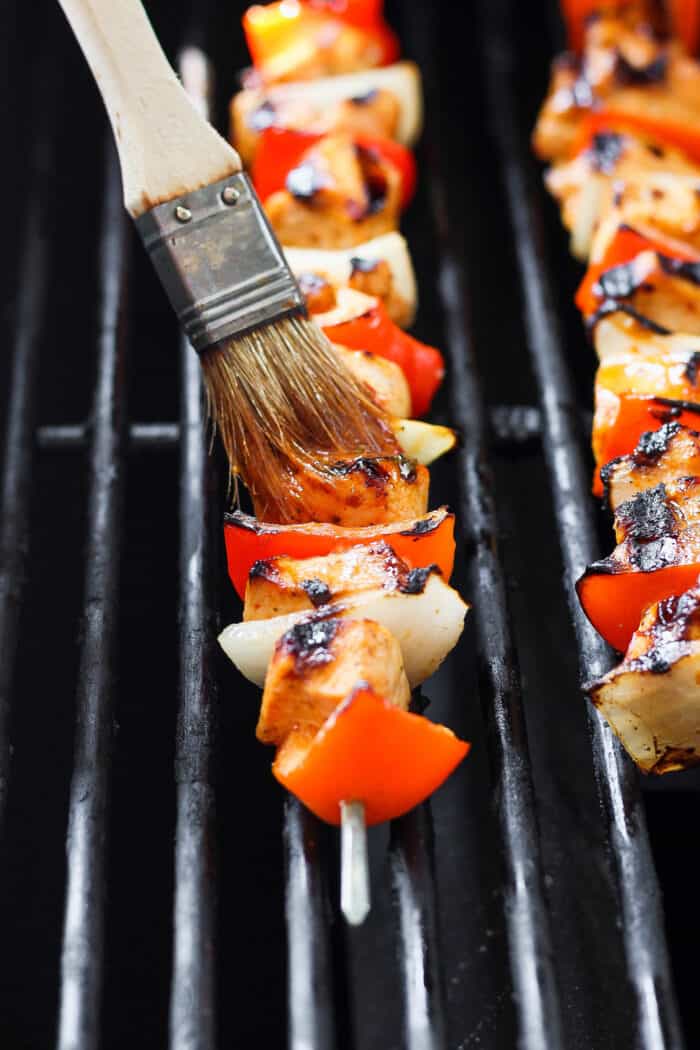 Sweet-spicy Chipotle Honey Chicken Kabobs bathe tender chicken in a honey-infused vinaigrette with a kick of spice. A marinade is brushed on chipotle honey chicken skewers as they cook on the grill.