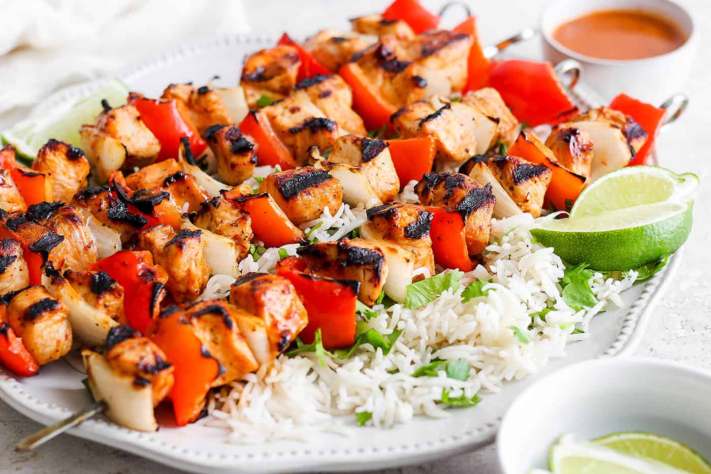 Sweet-spicy Chipotle Honey Chicken Kabobs bathe tender chicken in a honey-infused vinaigrette with a kick of spice. A platter of chipotle honey chicken kabobs is shown with cilantro rice.