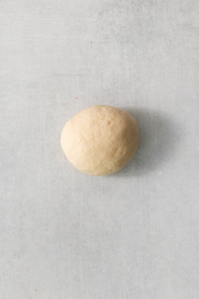 These copycat Rhodes Rolls are light and fluffy with a tender crumb and delicate flavor. Perfect for holiday meals! A dough round shown in a ball to make a rhodes roll.