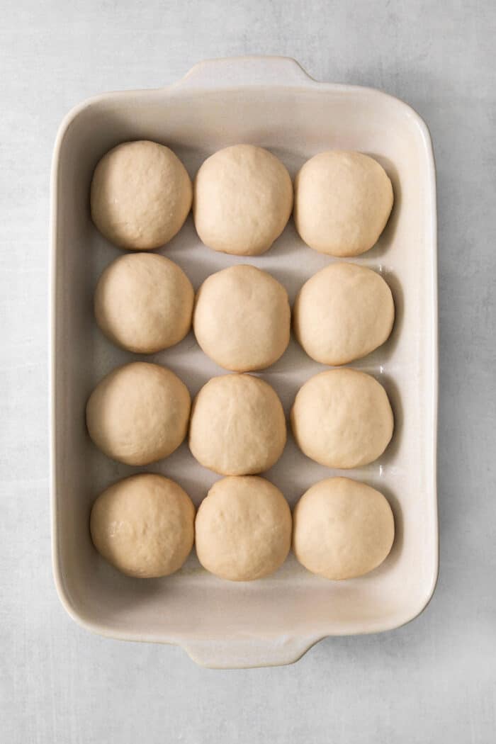 These copycat Rhodes Rolls are light and fluffy with a tender crumb and delicate flavor. Perfect for holiday meals! Rolls of dough are shown in a pan to make rhodes rolls.