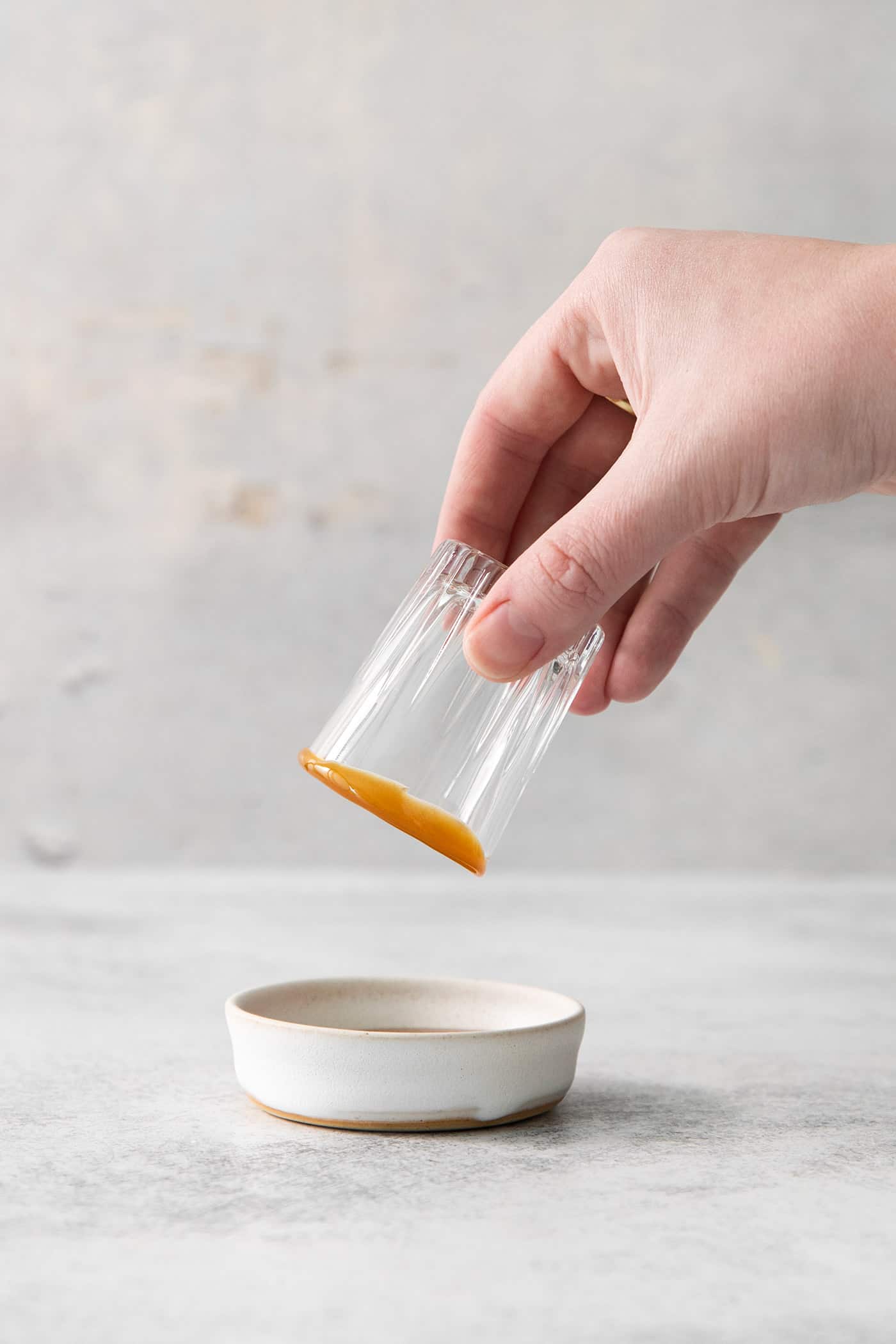 This Salted Nut Roll Shot is a fantastic twist on the salted nut roll candy bar with Rumchata, peanut butter whiskey, and vanilla vodka. A hand dips a shot glass into a bowl of caramel sauce.