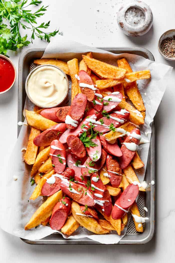 This Salchipapa recipe features crispy homemade french fries scattered with slices of beef hot dogs for a quick meal. A tray of salchipapa, including homemade french fries, hot dogs, and a small bowl of mayonnaise.