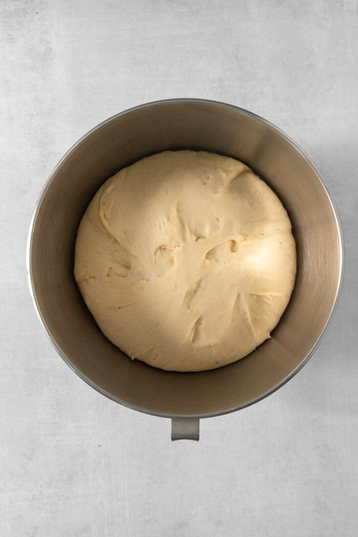 Sweet and pillowy Caramel Rolls make any morning special! Yeast dough and homemade caramel sauce make the ultimate breakfast treat. Proofed dough for caramel rolls in a silver bowl.