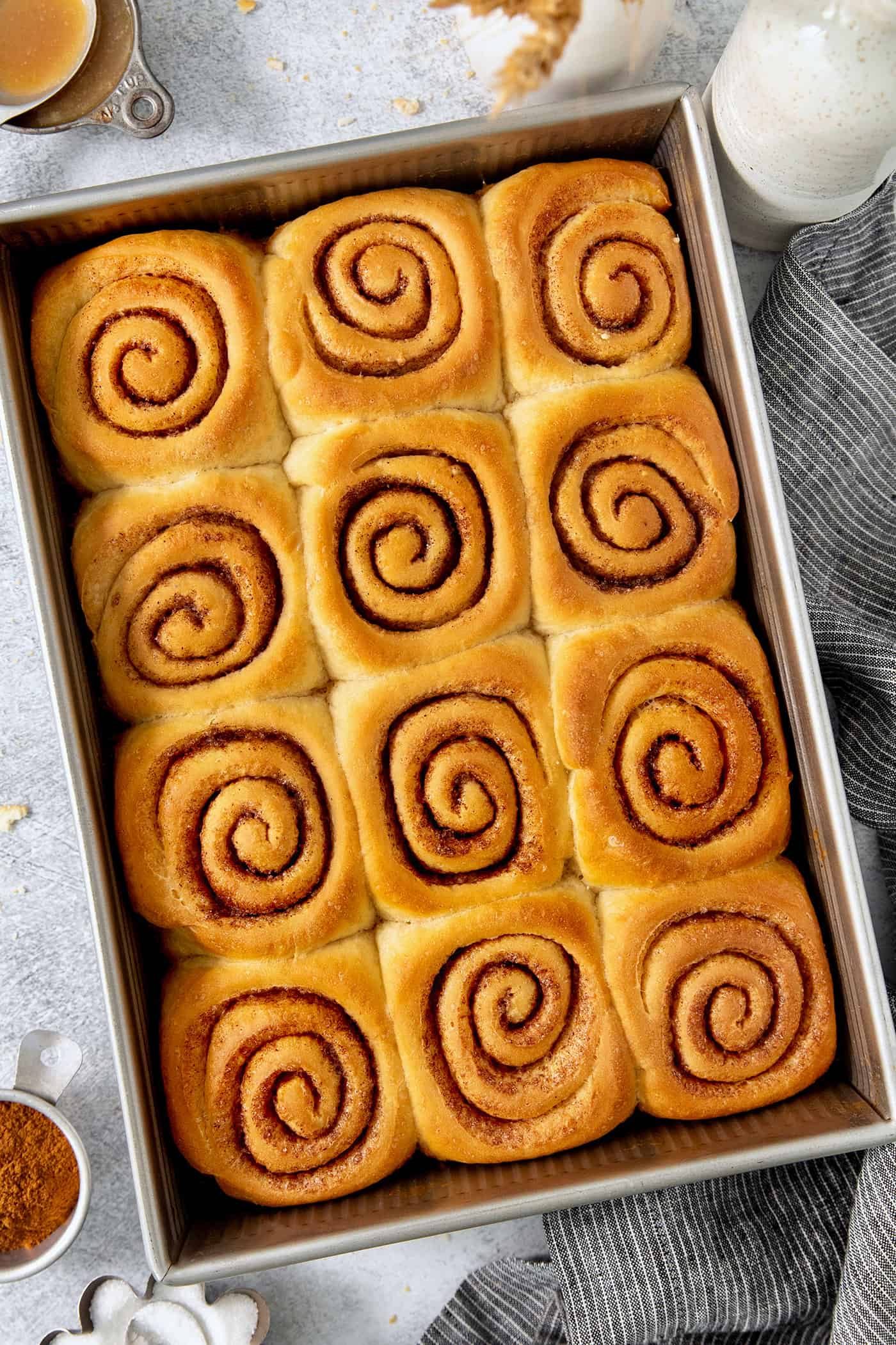 A pan of 12 caramel rolls is shown in a rectangular metal baking dish.