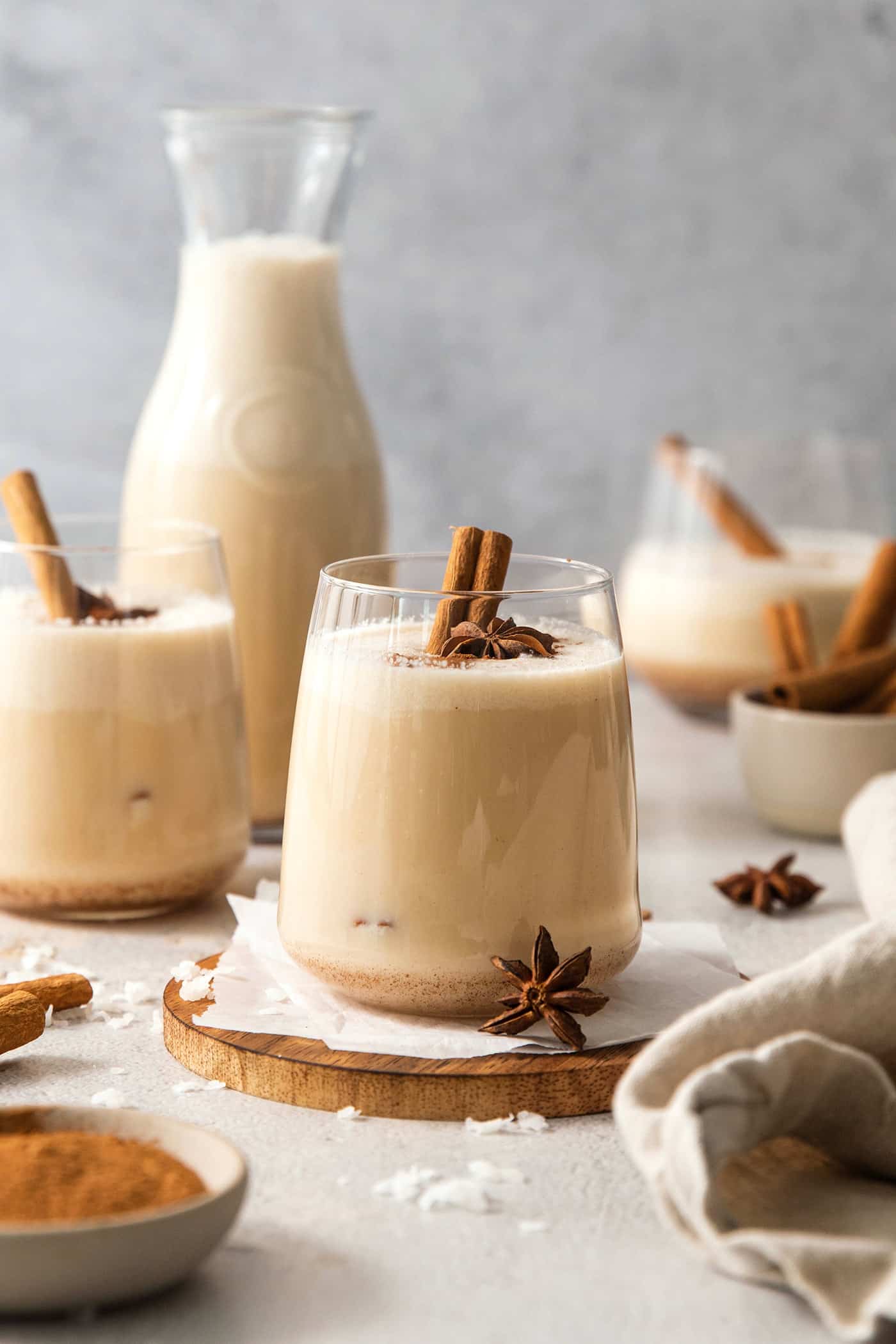 Glasses of coquito garnished with cinnamon sticks.
