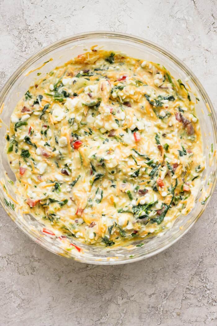 This protein-packed cottage cheese egg bake recipe combines creamy, fluffy eggs and cottage cheese with colorful veggies and crispy bacon. A top down shot of a bowl of cottage cheese egg bake.