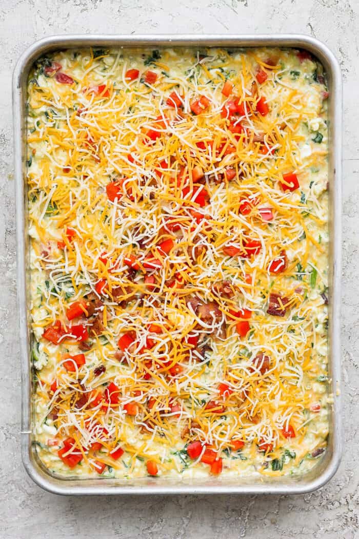 This protein-packed cottage cheese egg bake recipe combines creamy, fluffy eggs and cottage cheese with colorful veggies and crispy bacon. A pan of cottage cheese egg bake before being baked.