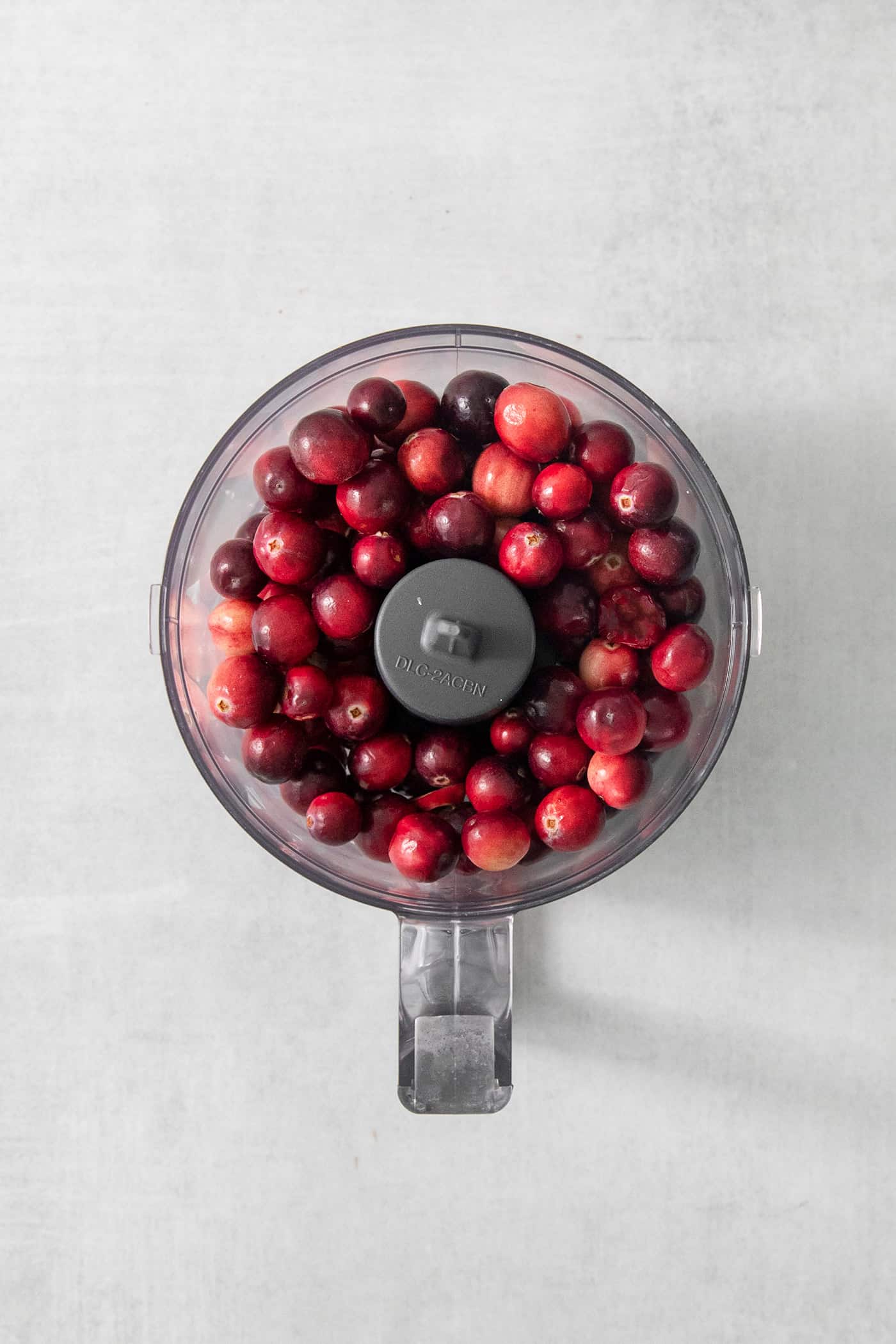 This Cranberry Jalapeno Dip is a quick and easy holiday appetizer! It features cream cheese and goat cheese and a cranberry-jalapeno relish. A top down shot of a food processor full of cranberries.