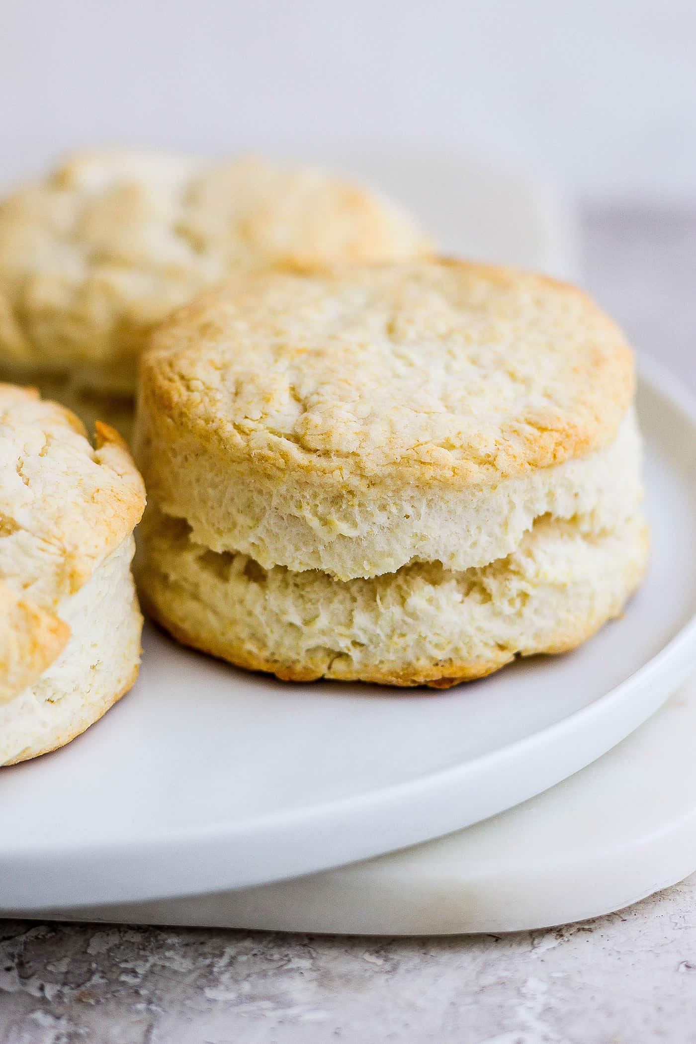 Rich, tender Cream Biscuits need just 3 simple ingredients and 15 minutes to make! Serve them with brunch or a hot bowl of homemade soup. A side view of a white plate of 3 cream biscuits.