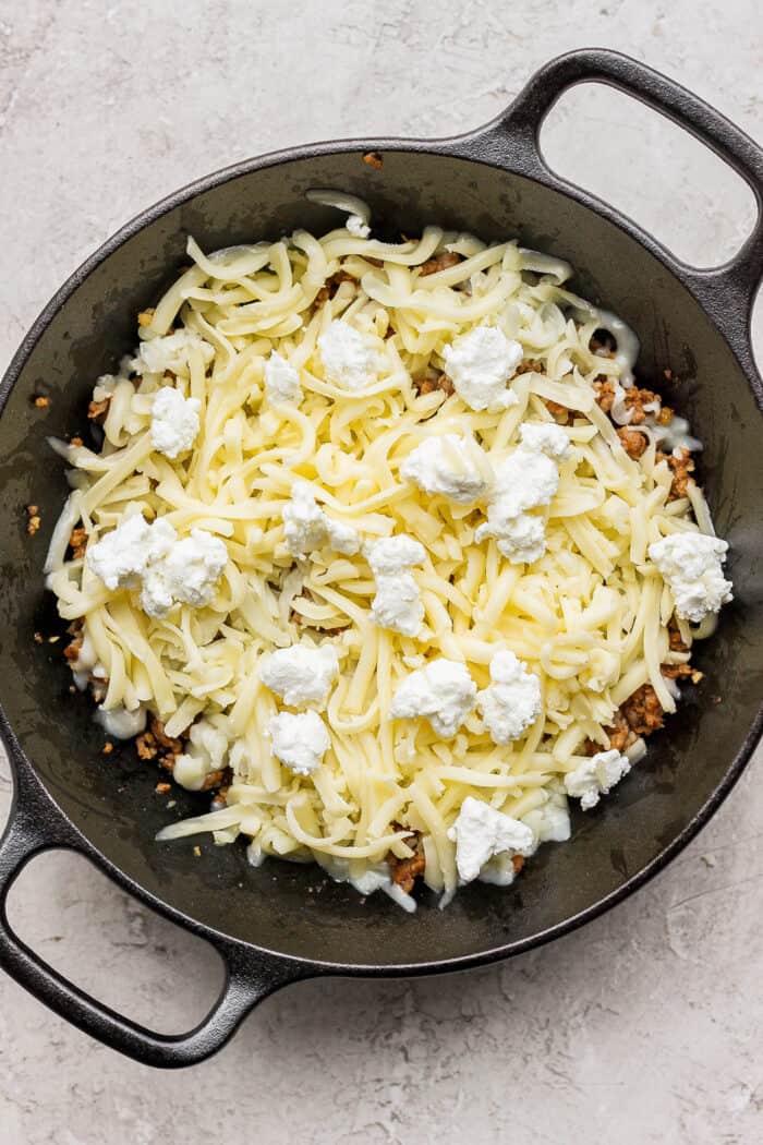Creamy and just a little spicy, Queso Fundido is an easy, go-to dip! Melted cheese and chorizo are topped with fresh tomatoes and jalapeno. Goat cheese crumbles are layered on top of Jack and Oaxaca cheeses and chorizo in a cast iron skillet.