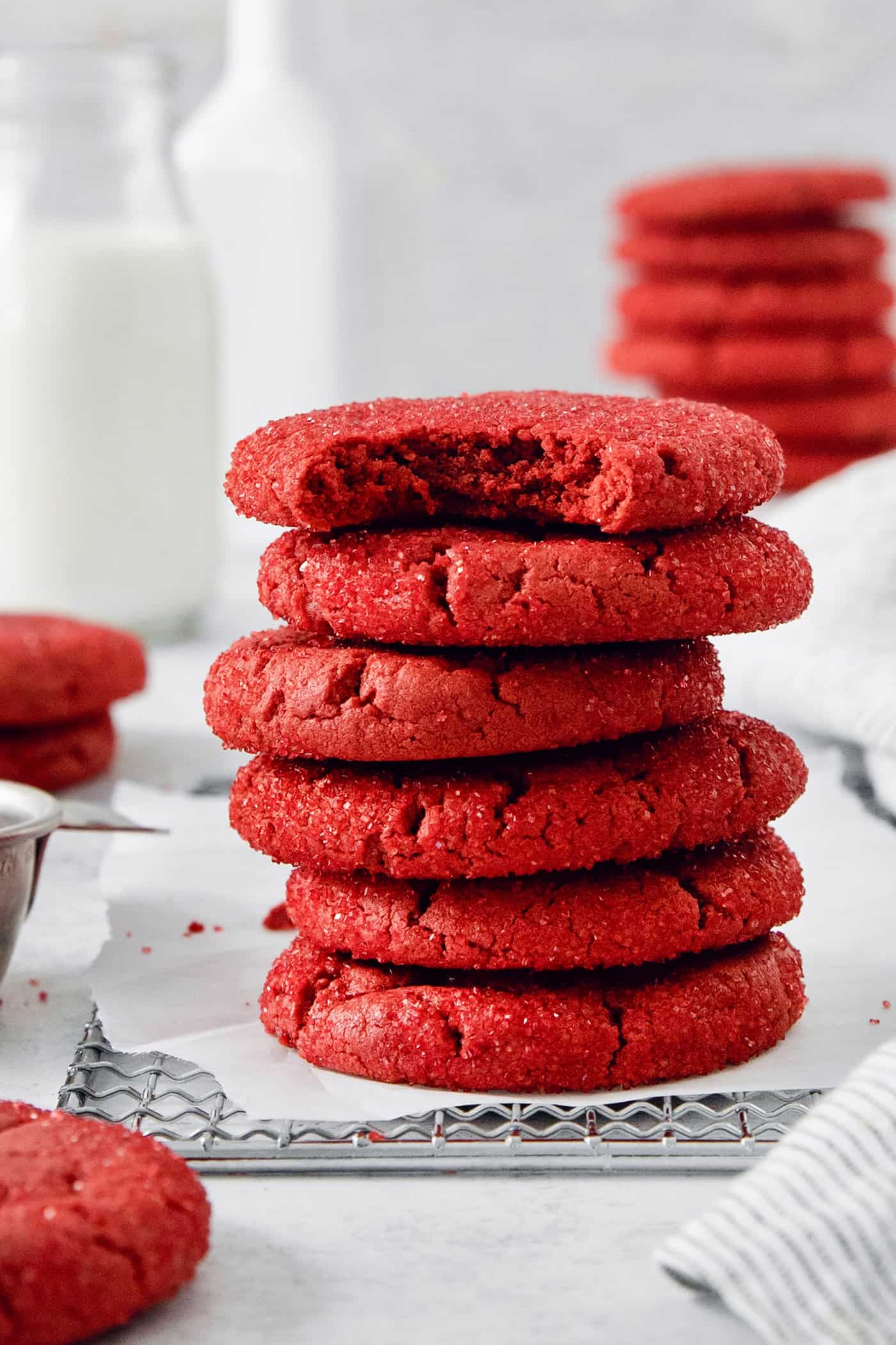These Red Velvet Cookies are soft and chewy, with a crisp sugar coating and a hint of cocoa and vanilla for flavor. A stack of red velvet cookies, with the top cookie having a bite taken out.