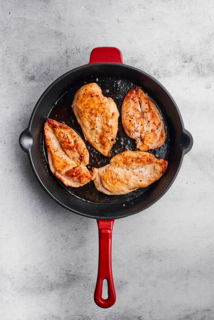 Creamy Chicken Madeira pairs tender chicken breasts with bright asparagus in a rich sauce. Add savory sautéed mushrooms and sweet wine. Four pieces of chicken breast brown in a skillet.
