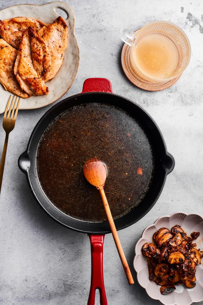 Creamy Chicken Madeira pairs tender chicken breasts with bright asparagus in a rich sauce. Add savory sautéed mushrooms and sweet wine. A wooden spoon stirs a skillet.