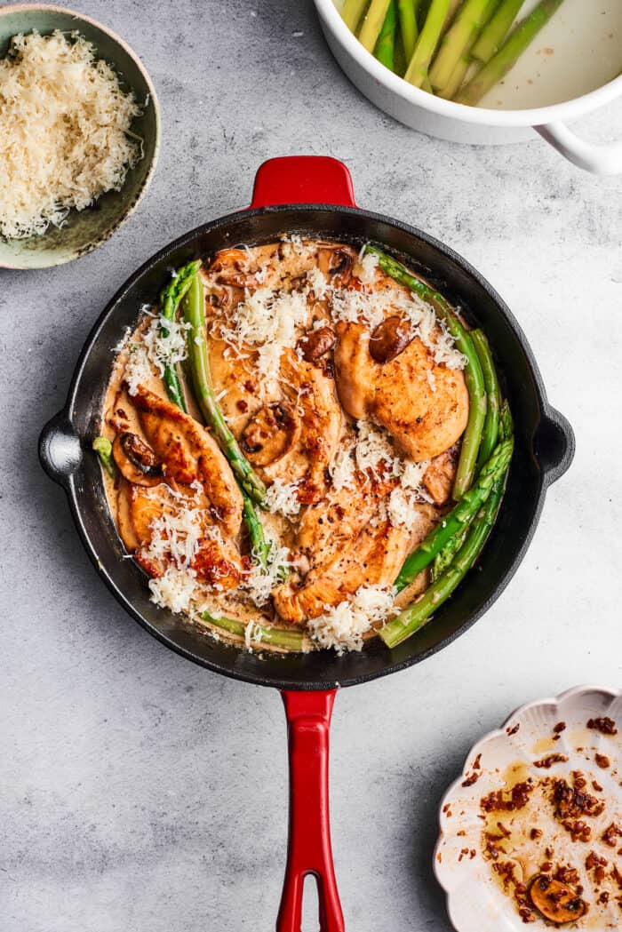 Creamy Chicken Madeira pairs tender chicken breasts with bright asparagus in a rich sauce. Add savory sautéed mushrooms and sweet wine. A skillet full of chicken madeira shows asparagus, chicken breast, mushrooms, and cream sauce.